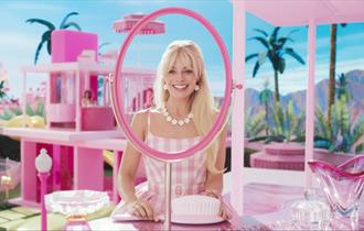 Margot Robbie as Barbie in a pink dreamhouse