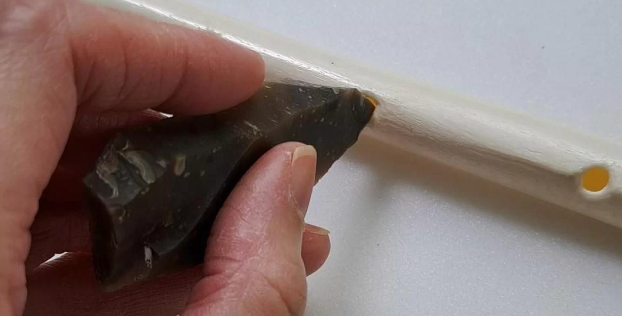 Hand carving a hole into a bone with a piece of flint