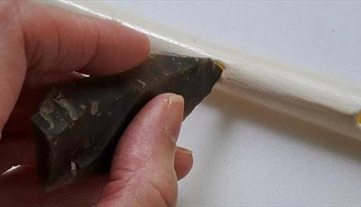 Hand carving a hole into a bone with a piece of flint