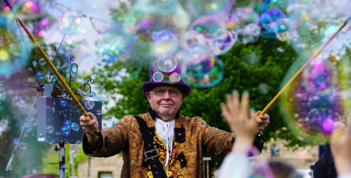 Bubbleman in a top hat and colourful jacket surrounded by bubbles