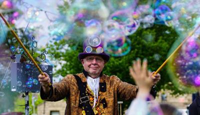 Bubbleman in a top hat and colourful jacket surrounded by bubbles