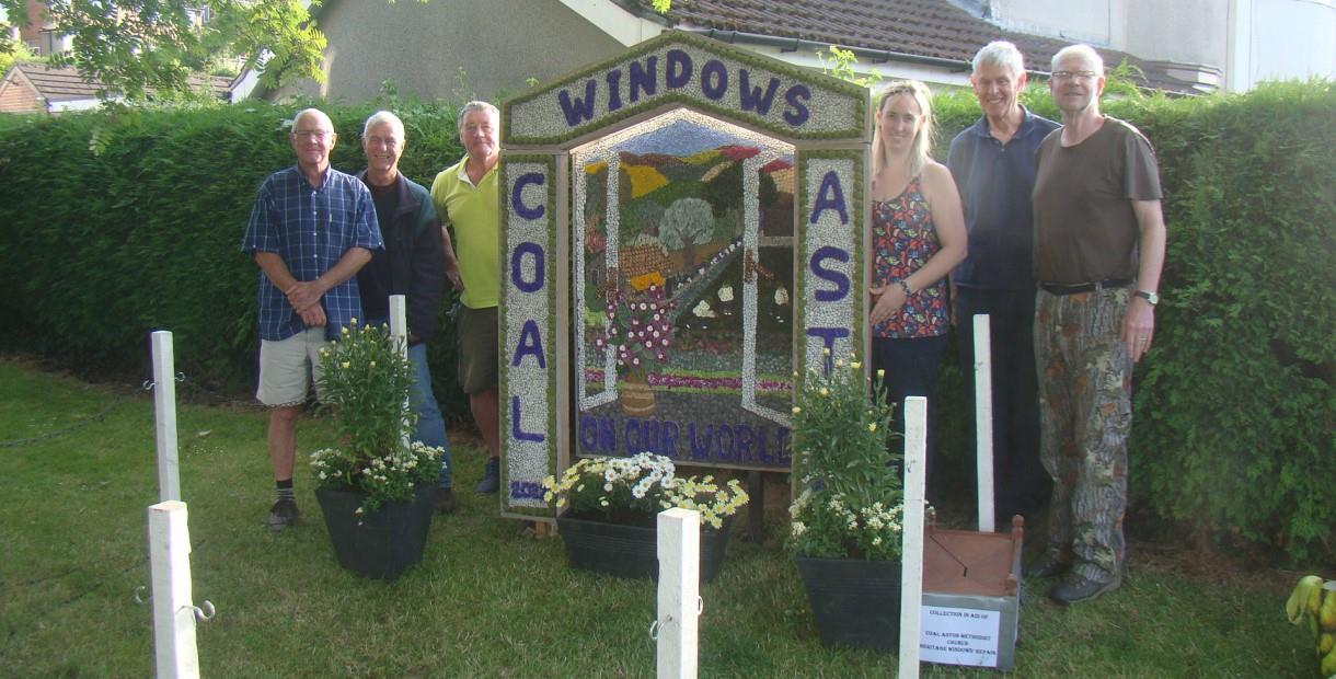 Three people stood either side of a Well Dressing