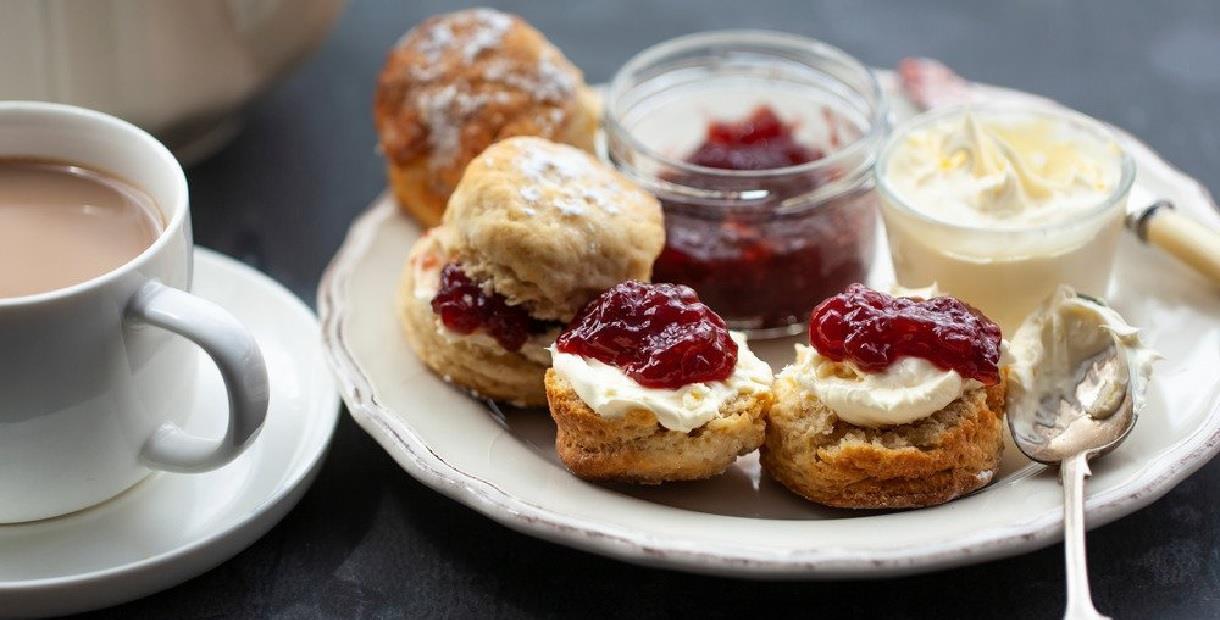 Tea and scones topped with jam and clotted cream.
