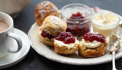 Tea and scones topped with jam and clotted cream.
