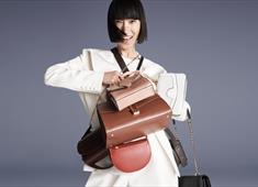 Lady smiling holding lots of designer handbags