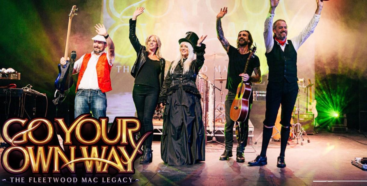 Members of the Fleetwood Mac legacy band waving on stage