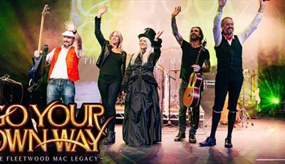 Members of the Fleetwood Mac legacy band waving on stage