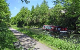 The John Varley II narrowboat cruising through Chesterfield Canal surrounded by trees and greenery