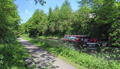 The John Varley II narrowboat cruising through Chesterfield Canal surrounded by trees and greenery