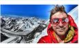 Kenton Cool wearing a red jacket and sunglasses on a mountain