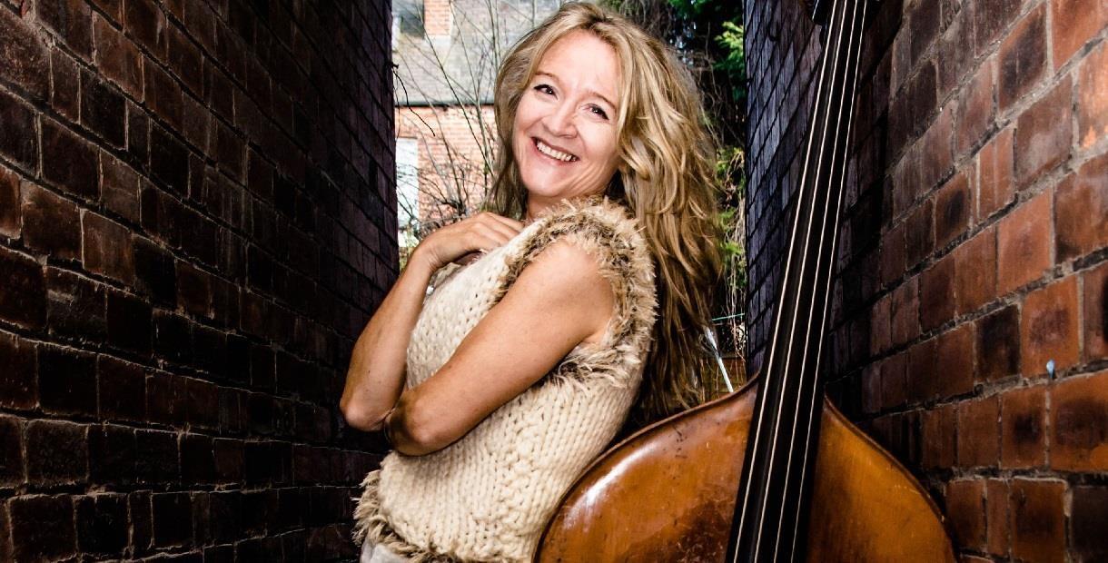 Nicola Farnon leaning against a double bass smiling