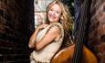 Nicola Farnon leaning against a double bass smiling