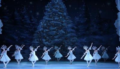 Ballet dancers in white dresses with snowflake crowns dancing on stage