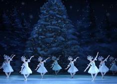 Ballet dancers in white dresses with snowflake crowns dancing on stage