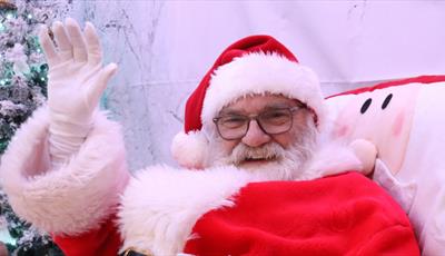 Santa is smiling and waving at the camera
