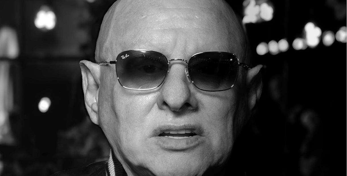 A black and white picture of Shaun Ryder's face, he is wearing dark sunglasses.