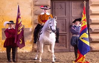 White horse and rider with a standard bearer on either side