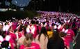 large crowd wearing pink t-shirts and light up bunny ears walking in the dark