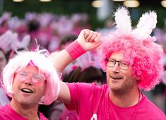 Two men in pink wigs and t-shirts smiling