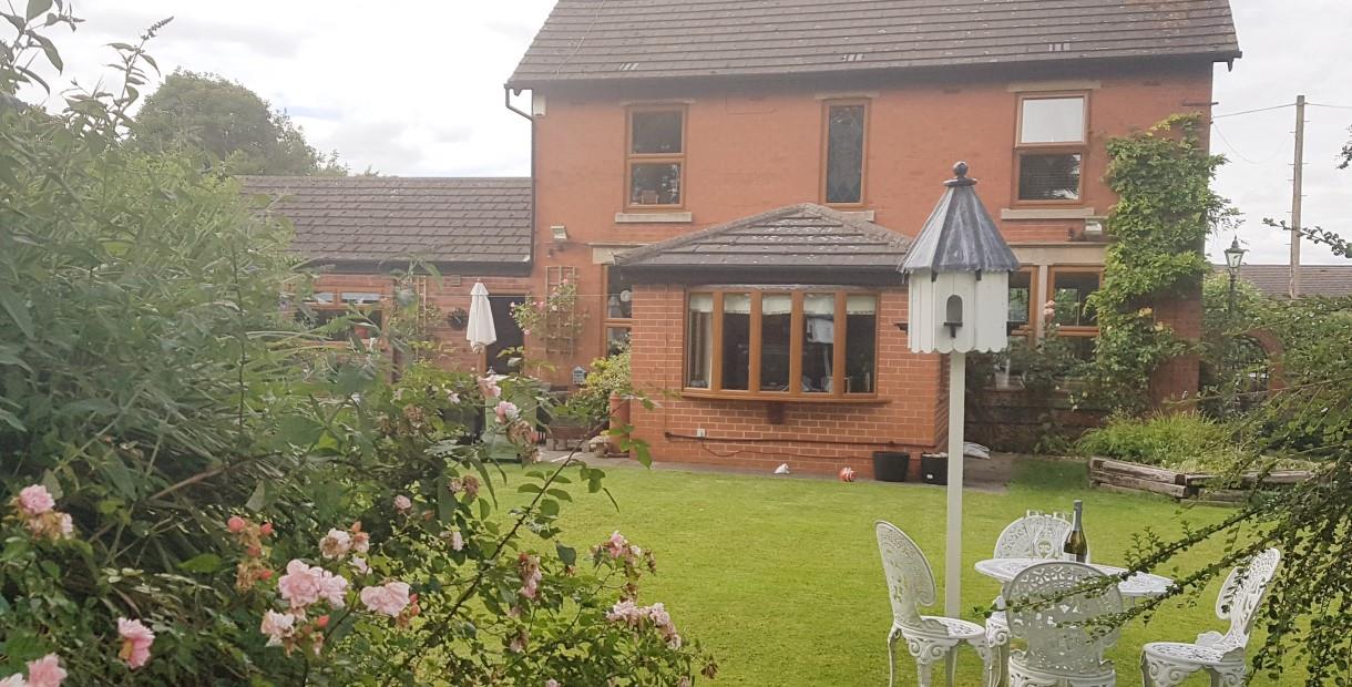 Well maintained back garden with patio furniture and rose bushes