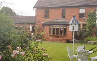 Well maintained back garden with patio furniture and rose bushes