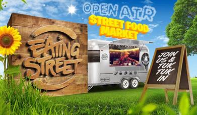 an image of a food truck in a park, a wooden sign reads 'Eating Street', text in the sky reads 'Open Air Street Food Market'