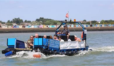 Brightlingsea foot ferry with passengers on board and beach huts in the back ground