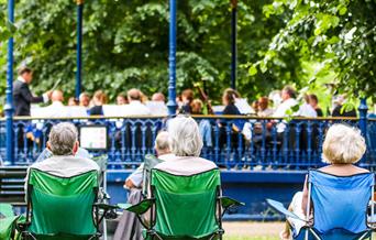 Audience on camping chairs watching a bandstand concert