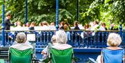 Audience on camping chairs watching a bandstand concert