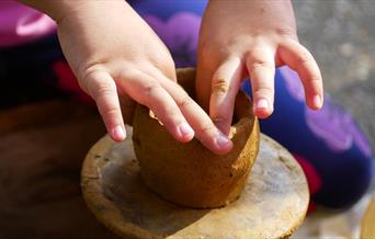 a child's hands making a clay pot