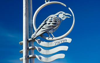 A metallic Raven way marker on the Town to Sea Trail