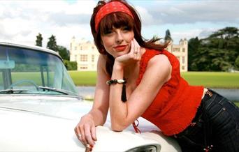 Joanna Eden leans on a white car.