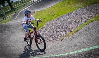 A child rides a bike on the pump track