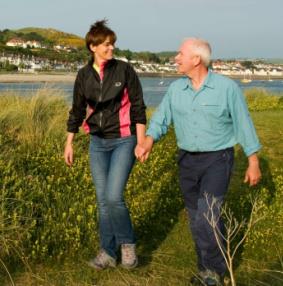 Couple walking and holding hands along Wales Coast Path