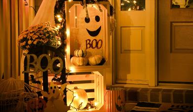 Small display of ghosts and white pumpkins with orange lights