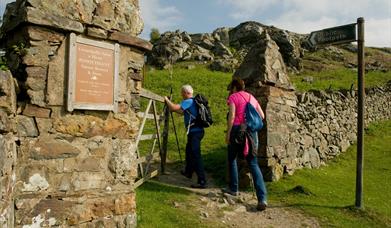 Two walkers at the gateway entry to Pensychnant Nature Reserve