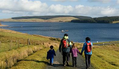 Teulu yn cerdded i gyfeiriad Llyn Brenig