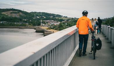 Beiciwr yn cerdded ar Bont Conwy