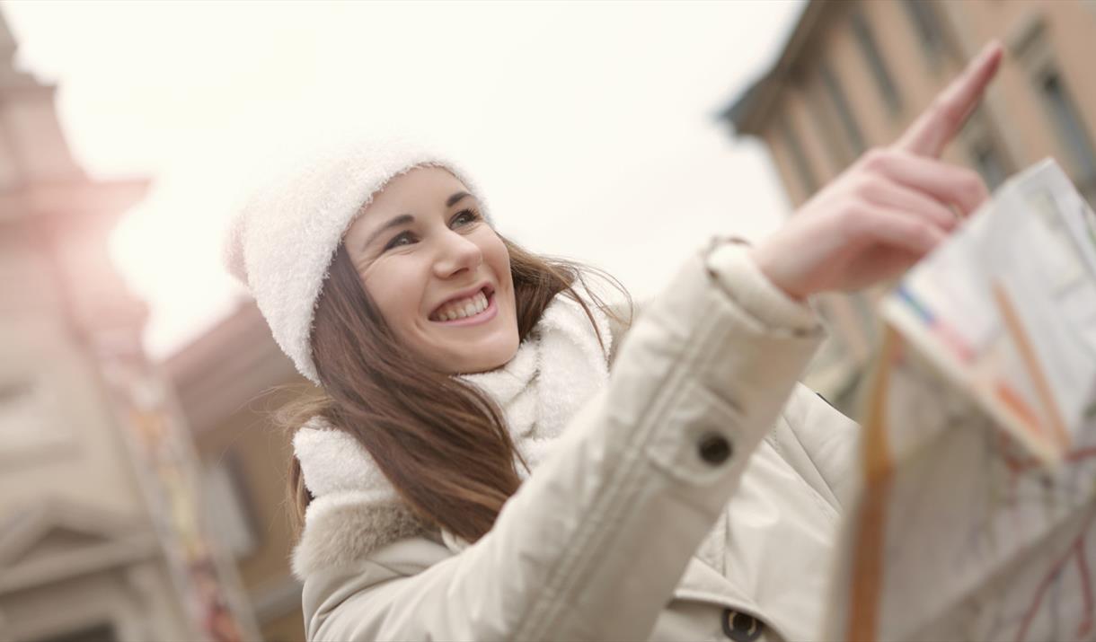 Person pointing forward in a white jacket and hat