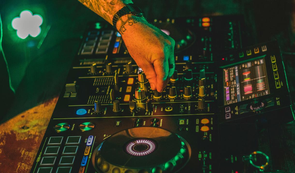 Electric mixing decks being operated by person with tattoos