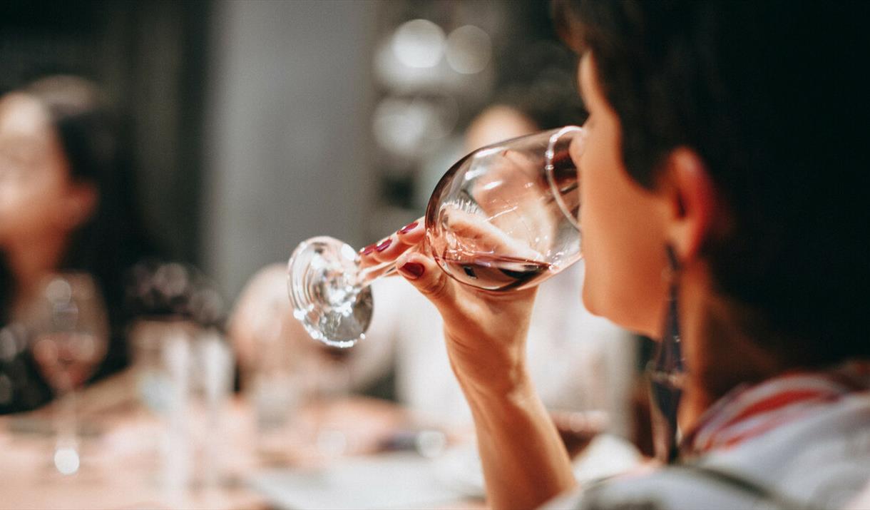 A person drinking from a clear wine glass