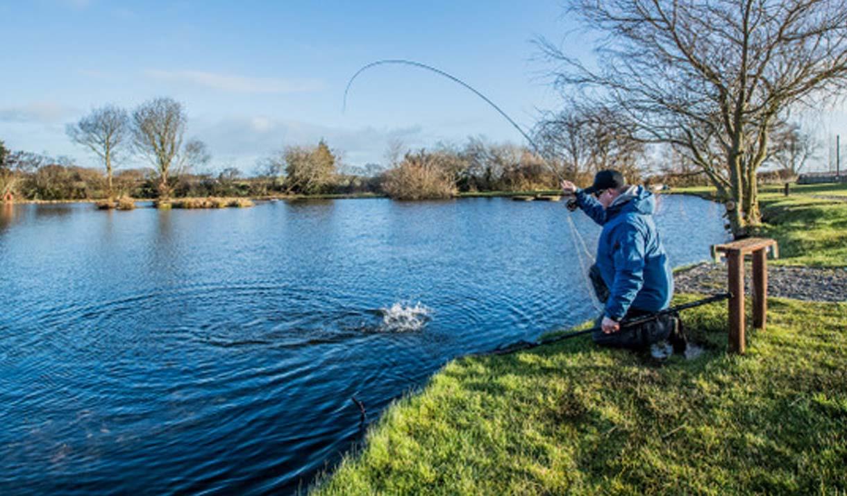 Man casting a fishing rod into trout lake