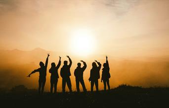 Silhouette of six people posing against a sunset
