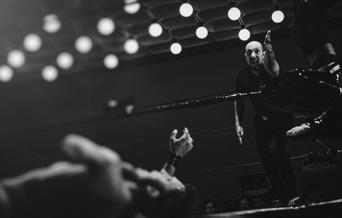 Wrestler down in the ring and referee gesturing with arm