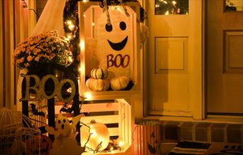 Small display of ghosts and white pumpkins with orange lights