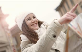 Person pointing forward in a white jacket and hat