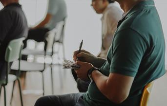 Person sitting in a chair taking notes on paper