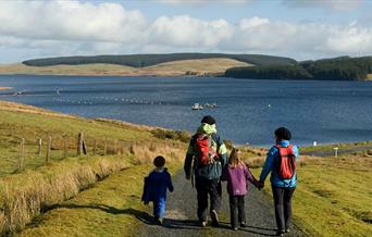 Teulu yn cerdded i gyfeiriad Llyn Brenig