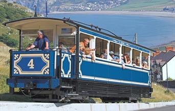 Tram Llandudno yn dringo i fyny Y Gogarth gyda Bae Llandudno yn y cefndir