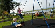Children playing on the swings in the play area, Llanfairfechan seafront